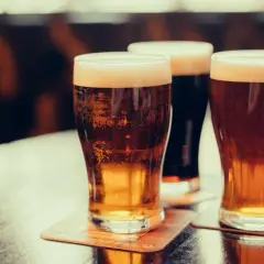 Trois verres de bière mousseuse sur des sous-bocks. Une bière bienfait pour se détendre.