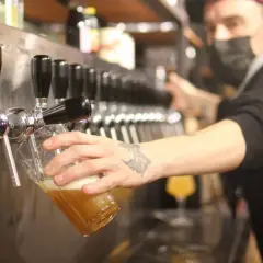 Un barman sert une bière blonde. Le taux alcool de cette bière est modéré, parfait pour une dégustation.