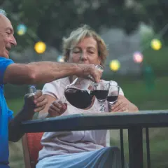 Un couple âgé profite d'un verre de vin par jour dans le jardin, sous des guirlandes lumineuses.