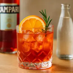 Un verre d'Americano, garni d'une tranche d'orange et d'une branche de romarin, prêt à être dégusté. La recette americano traditionnelle est simple et rafraîchissante.