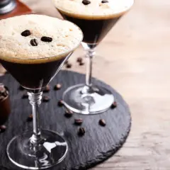 Deux martinis à l'espresso, parfaits pour une recette d'espresso martini. Grains de café et moulin en arrière-plan.
