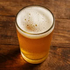 Un verre de bière dorée avec une mousse blanche sur une table en bois. La bière valeur nutritionnelle est un sujet de discussion.