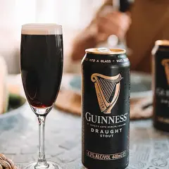 Une pinte de Guinness Draught Stout, avec son degré alcool de 4.2%, est servie à côté de canettes.