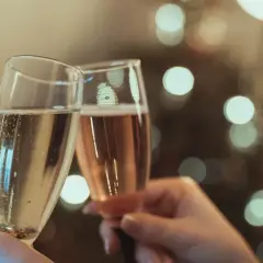 Deux flûtes de champagne s'entrechoquent, évoquant le plaisir et l'origine de cette boisson festive.