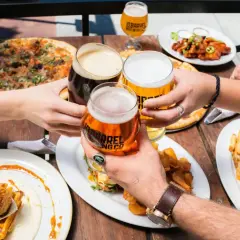 Un toast entre amis avec des bières à 11 degrés, pizza, burger et poulet frit.