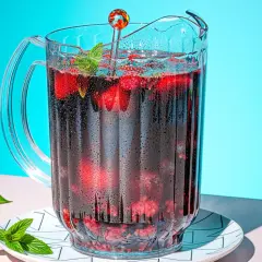 Un pichet de sangria maison pétillante, rempli de fruits rouges et de menthe, prêt à rafraîchir.