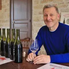 Pierre Jean Villa, vigneron souriant, présente une dégustation de vins. Bouteilles alignées, verre à la main, il partage sa passion.