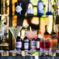 Cinq cocktails colorés, parfaits comme boisson pour ouvrir l'appétit, sont alignés sur un bar.