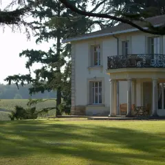 Le **château Pey la Tour** se dresse majestueusement, entouré de vignobles verdoyants sous un ciel clair. Une pelouse impeccable invite à la détente.