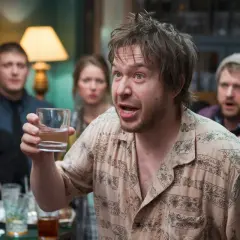 Un homme tient un verre d'eau, expliquant comment faire baisser l'alcool à ses amis surpris lors d'une soirée.