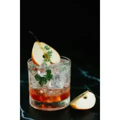Un cocktail rafraîchissant avec une tranche de poire et une touche de thym, parfait pour un twist bière estival.