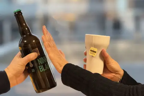 Une main repousse une bouteille de bière, l'autre tient une tasse de thé Earl Grey. Un choix pour un cocktail sans rhum.