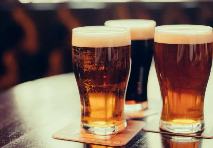 Trois verres de bière mousseuse sur des sous-bocks. Une bière bienfait pour se détendre.
