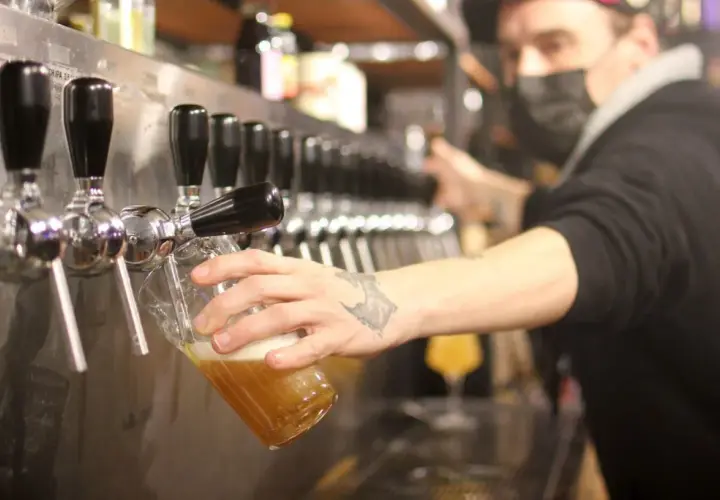 Un barman sert une bière blonde. Le taux alcool de cette bière est modéré, parfait pour une dégustation.