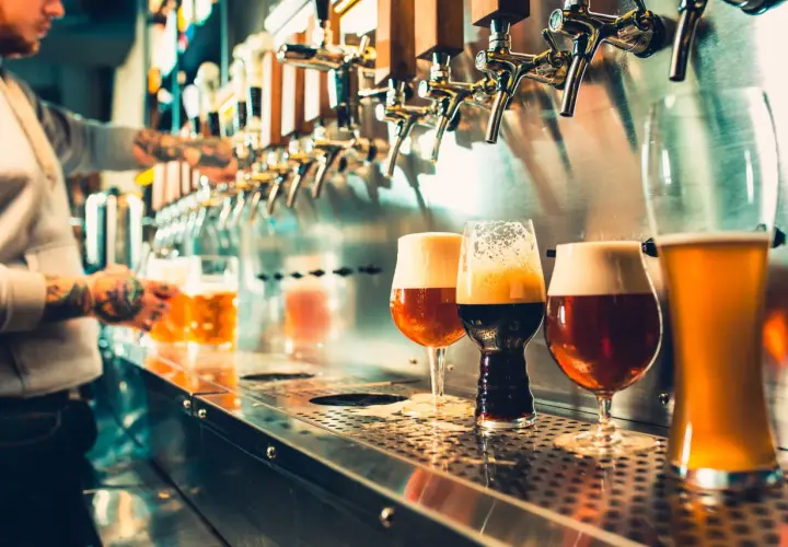 Barman sert des bières artisanales. Est-ce que la bière hydrate ? La réponse est complexe, mais ces verres invitent à la dégustation.