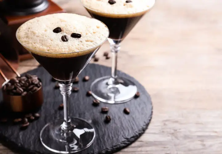 Deux martinis à l'espresso, parfaits pour une recette d'espresso martini. Grains de café et moulin en arrière-plan.