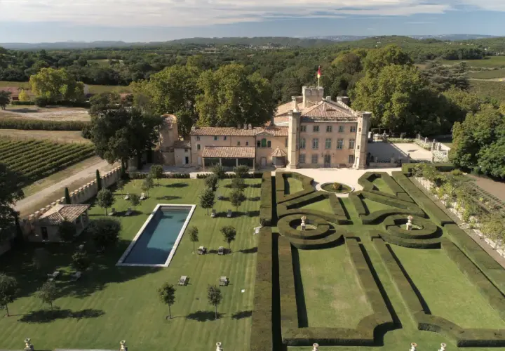 Vue aérienne du **château Beaulieu**, un domaine viticole pittoresque, avec ses jardins à la française, sa piscine et ses vignobles.