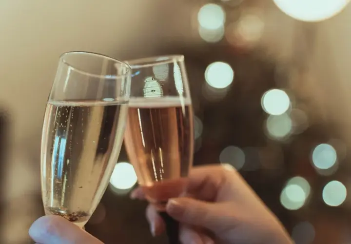 Deux flûtes de champagne s'entrechoquent, évoquant le plaisir et l'origine de cette boisson festive.