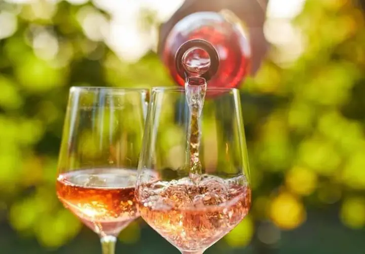 Un verre de rosé est servi dans un autre verre, sous un soleil radieux. Un moment parfait pour boire du rosé tous les jours.