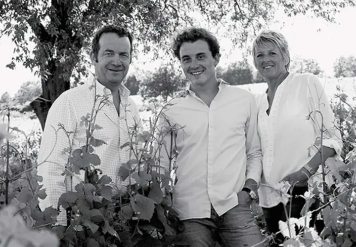 Trois générations de la famille Arnoux Lachaux sourient dans un vignoble, entourés de vignes.