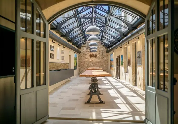 L'intérieur lumineux de la Maison Champy, avec son toit de verre, ses tables en bois et ses murs en pierre, invite à la dégustation.