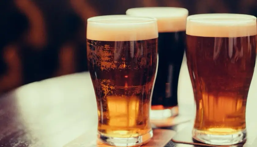 Trois verres de bière mousseuse sur des sous-bocks. Une bière bienfait pour se détendre.