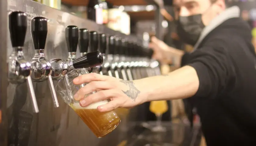 Un barman sert une bière blonde. Le taux alcool de cette bière est modéré, parfait pour une dégustation.
