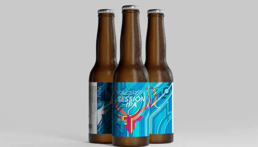 Trois bouteilles de bière ambrée, dont une avec une étiquette colorée "VOLCELEST SESSION IPA" aux motifs géométriques bleus et roses.
