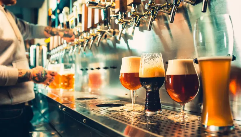 Barman sert des bières artisanales. Est-ce que la bière hydrate ? La réponse est complexe, mais ces verres invitent à la dégustation.