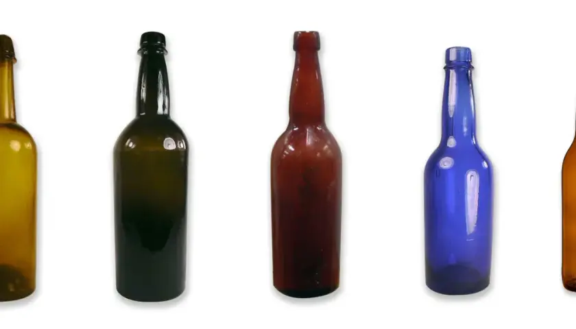 Cinq bouteilles de différentes couleurs et tailles, dont une bouteille de bière ambrée, alignées sur fond blanc.