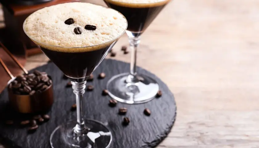 Deux martinis à l'espresso, parfaits pour une recette d'espresso martini. Grains de café et moulin en arrière-plan.