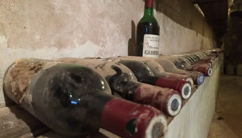 Des bouteilles de vin poussiéreuses s'alignent dans une cave. Combien de temps pour éliminer une bouteille de vin ? La réponse dépend de la patience du dégustateur.