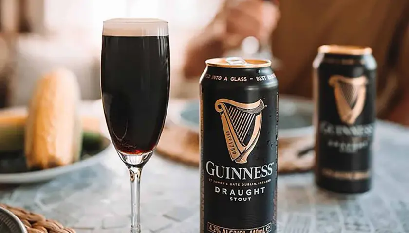 Une pinte de Guinness Draught Stout, avec son degré alcool de 4.2%, est servie à côté de canettes.