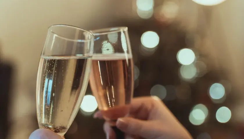 Deux flûtes de champagne s'entrechoquent, évoquant le plaisir et l'origine de cette boisson festive.