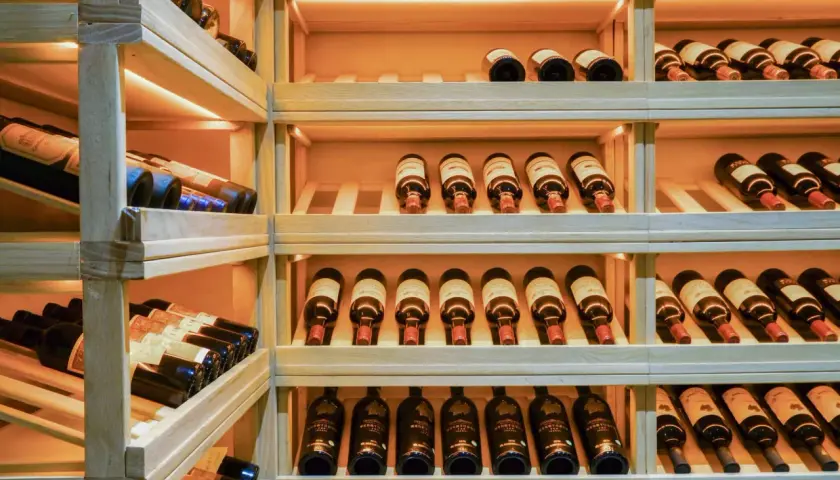 Étagères en bois remplies de bouteilles de vin. Une belle cave à vin pour bien choisir.