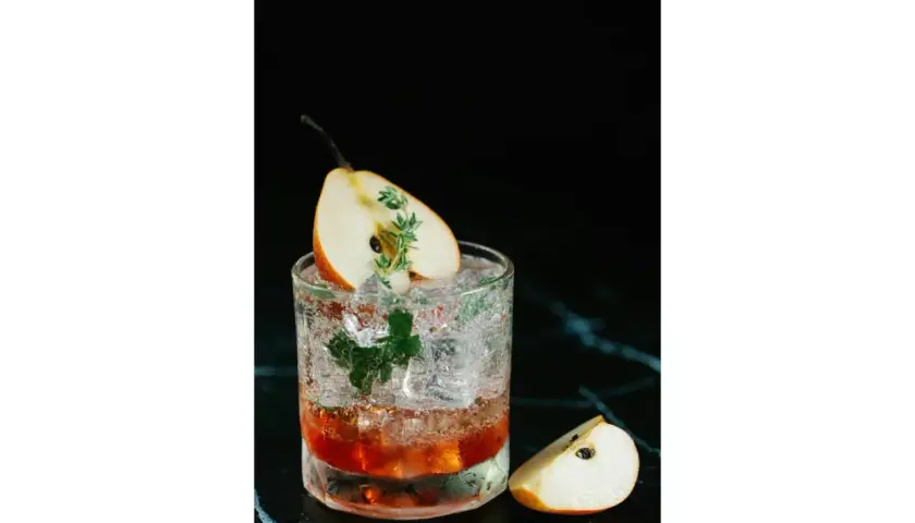Un cocktail rafraîchissant avec une tranche de poire et une touche de thym, parfait pour un twist bière estival.