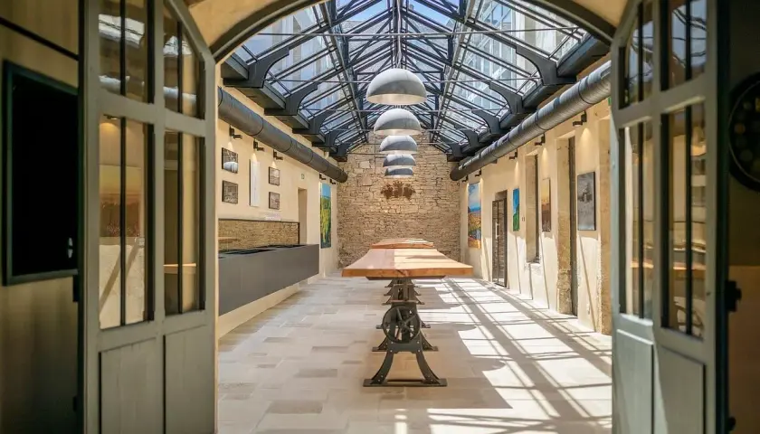 L'intérieur lumineux de la Maison Champy, avec son toit de verre, ses tables en bois et ses murs en pierre, invite à la dégustation.