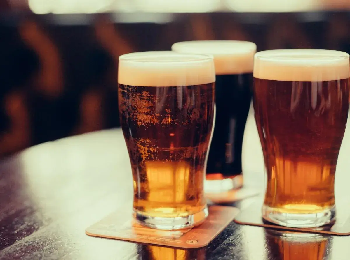 Trois verres de bière mousseuse sur des sous-bocks. Une bière bienfait pour se détendre.