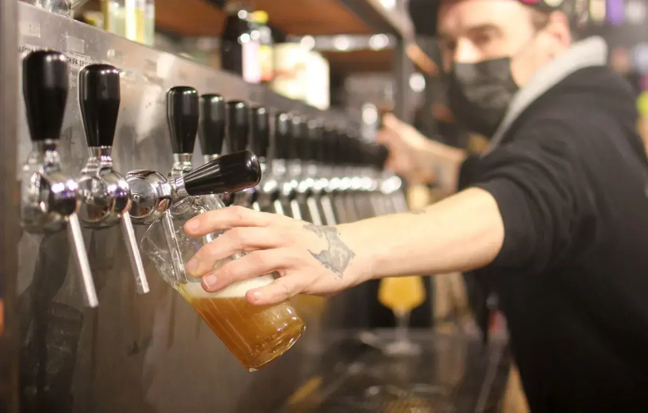 Un barman sert une bière blonde. Le taux alcool de cette bière est modéré, parfait pour une dégustation.