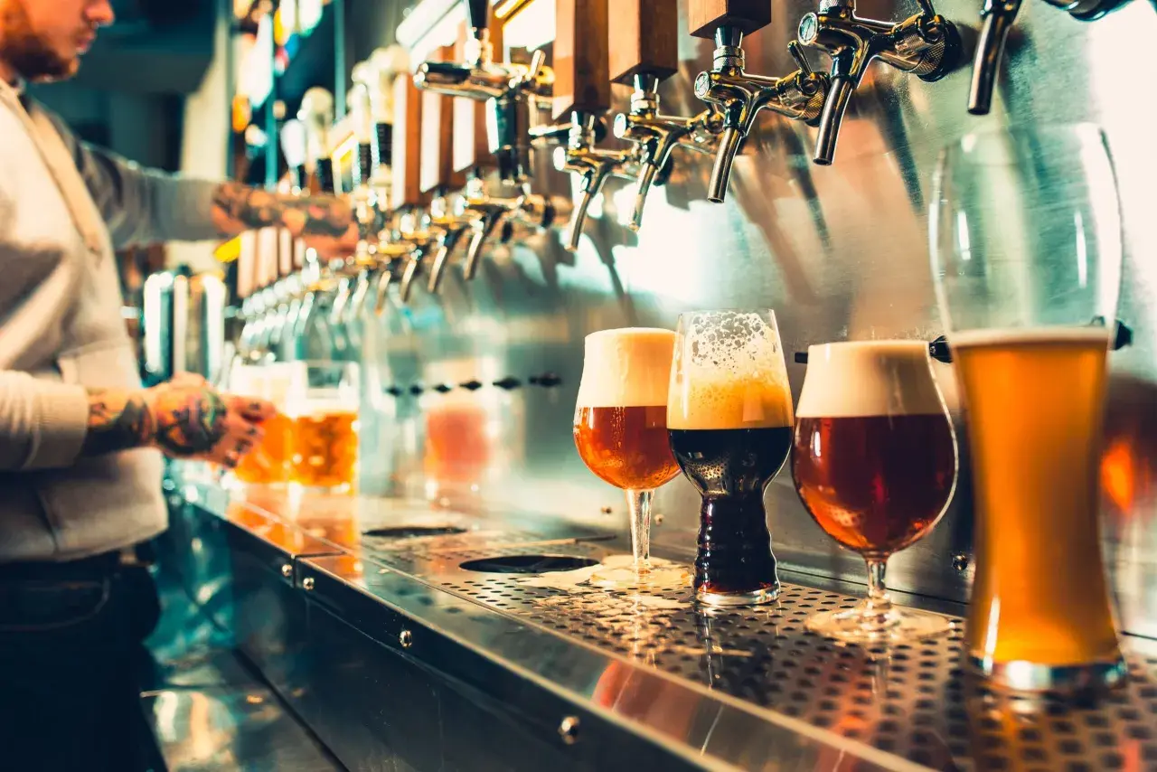 Barman sert des bières artisanales. Est-ce que la bière hydrate ? La réponse est complexe, mais ces verres invitent à la dégustation.
