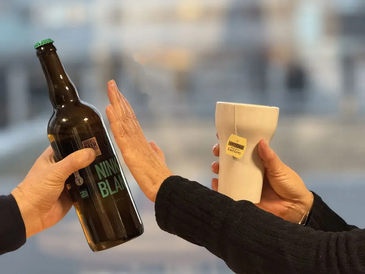 Une main repousse une bouteille de bière, l'autre tient une tasse de thé Earl Grey. Un choix pour un cocktail sans rhum.