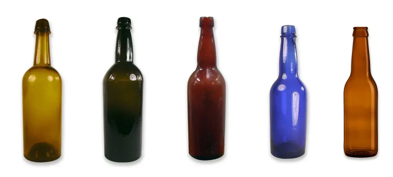 Cinq bouteilles de différentes couleurs et tailles, dont une bouteille de bière ambrée, alignées sur fond blanc.