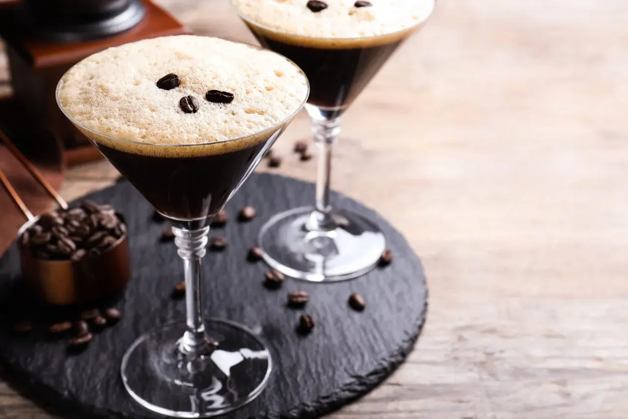 Deux martinis à l'espresso, parfaits pour une recette d'espresso martini. Grains de café et moulin en arrière-plan.