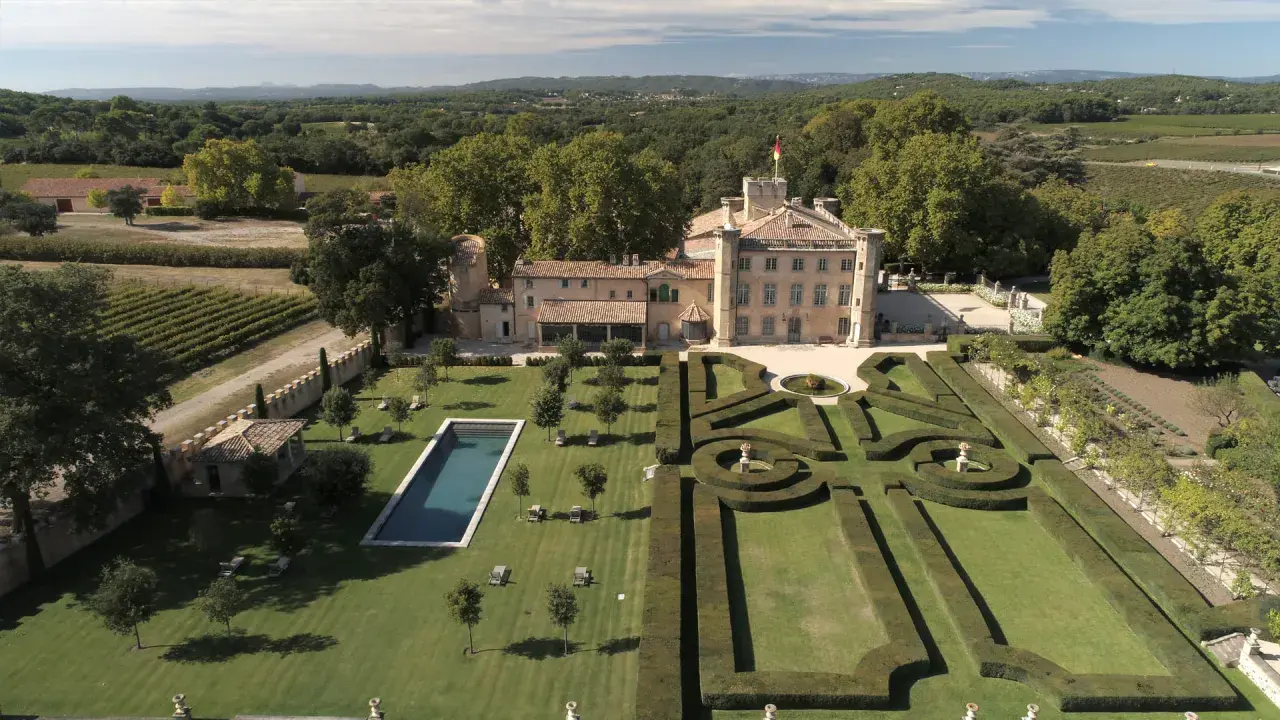 Vue aérienne du **château Beaulieu**, un domaine viticole pittoresque, avec ses jardins à la française, sa piscine et ses vignobles.