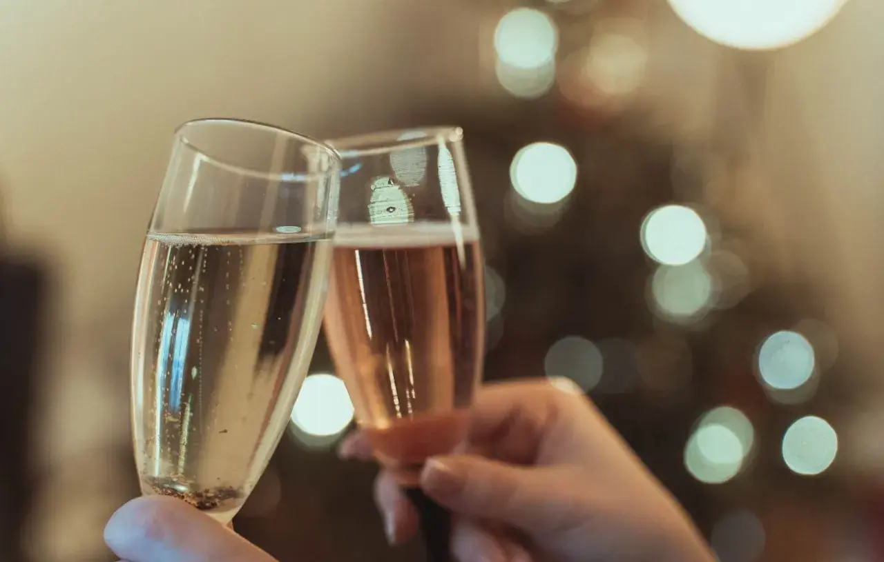 Deux flûtes de champagne s'entrechoquent, évoquant le plaisir et l'origine de cette boisson festive.