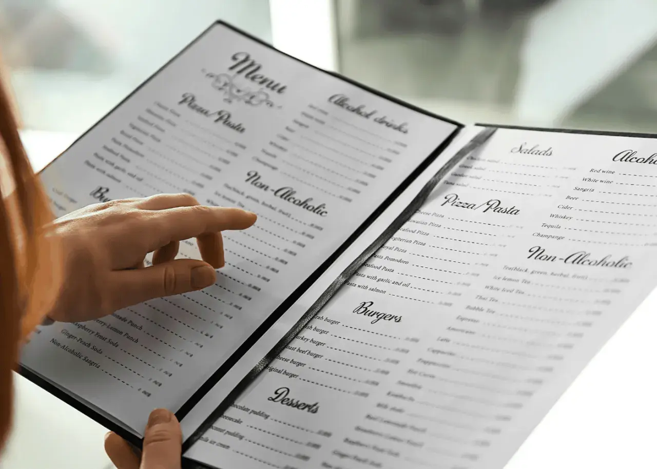 Une main parcourt le menu, cherchant le vin au verre parfait pour accompagner son repas.