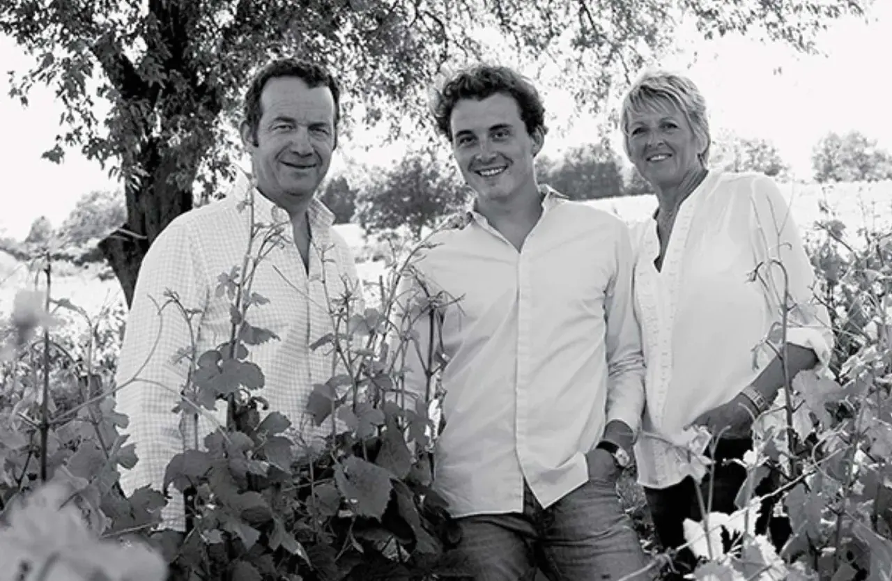 Trois générations de la famille Arnoux Lachaux sourient dans un vignoble, entourés de vignes.