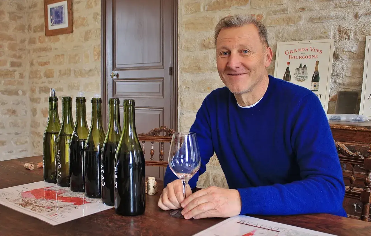 Pierre Jean Villa, vigneron souriant, présente une dégustation de vins. Bouteilles alignées, verre à la main, il partage sa passion.