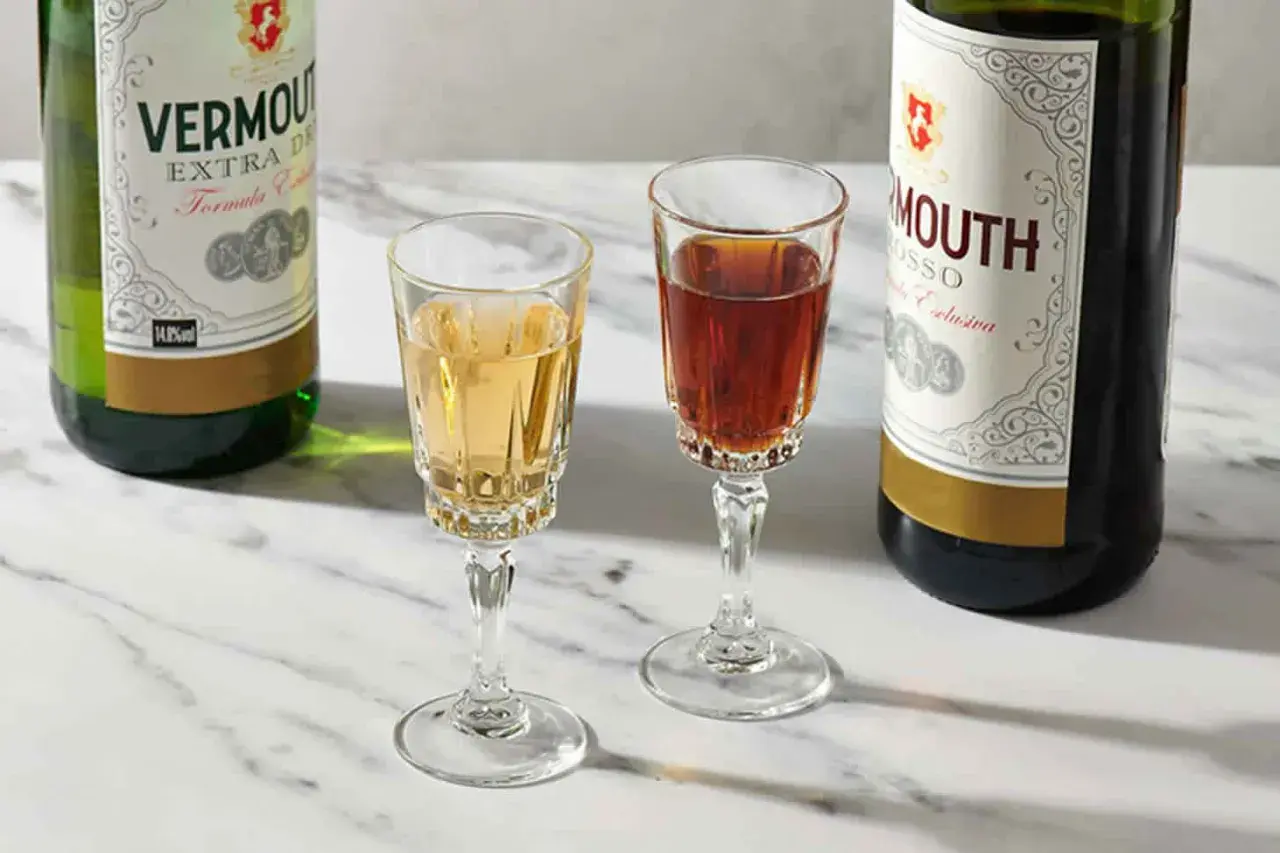 Deux verres de vermouth blanc et rouge, accompagnés de leurs bouteilles. Un apéritif raffiné.