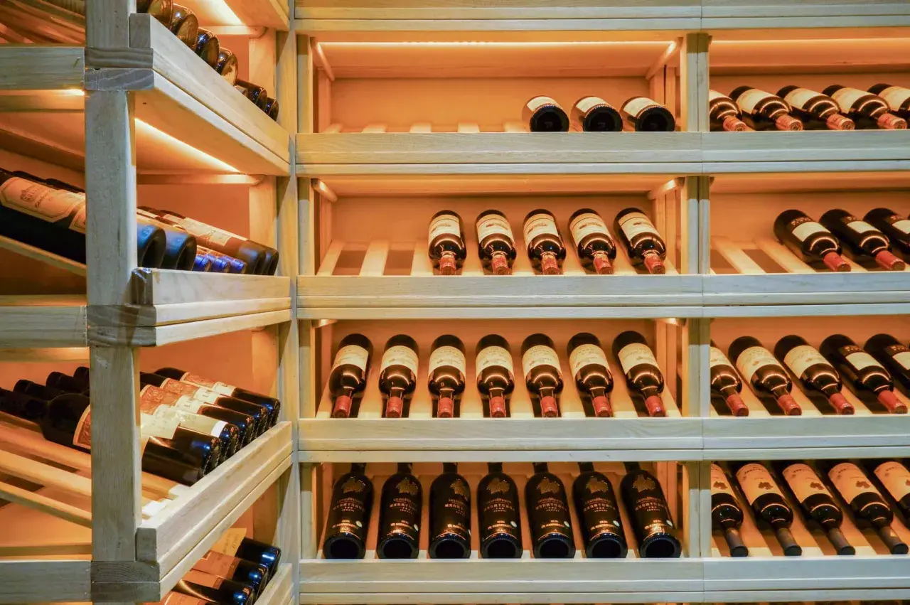 Étagères en bois remplies de bouteilles de vin. Une belle cave à vin pour bien choisir.